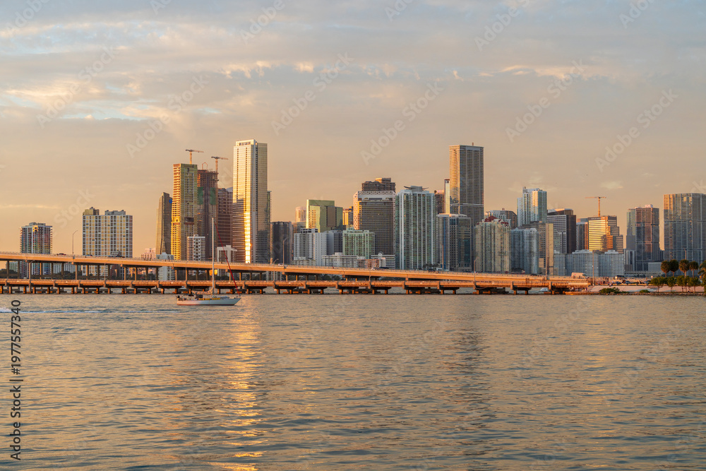 Fototapeta premium Miami skyline at golden hour with MacArthur Causeway and sunlight reflections on Biscayne Bay