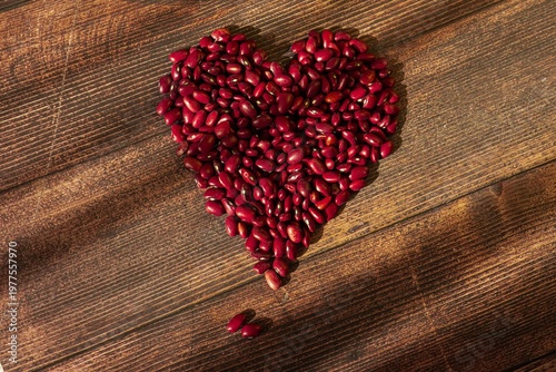 red kidney beans arranged in a heart shape on a dark textured wooden background