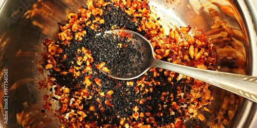 Spicy snack mix with sesame seeds and chili flakes in metal bowl