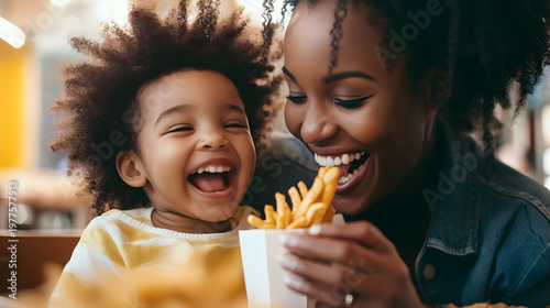 Mother and child sharing a joyful moment with french fries