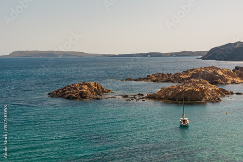 Sailboat stranded on the shore next to several rock formations