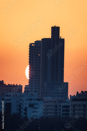 Sun Setting Behind a Tall Building with Orange Hues