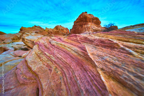 Fotografie Colorful Sandstone Layers and Striations Under Blue Sky in Dramatic Desert Lands