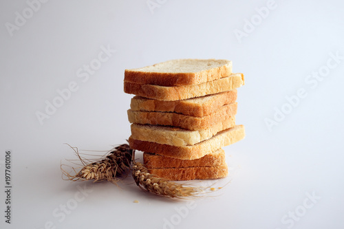 Sliced white toast bread and wheat ears on white background.