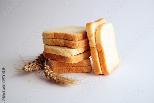 Sliced white toast bread and wheat ears on white background.