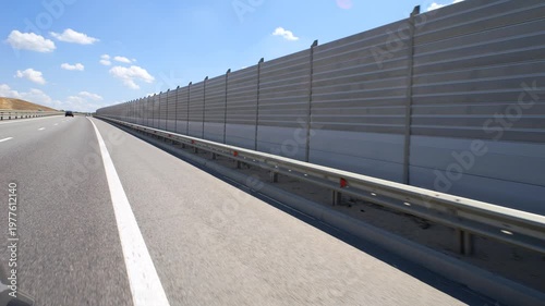 Soundproof fencing along the expressway. Hyperlapse. Shooting in motion. A barrier near an asphalt road. Highway. The highway.