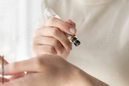 Closeup of a woman applying roll-on perfume.