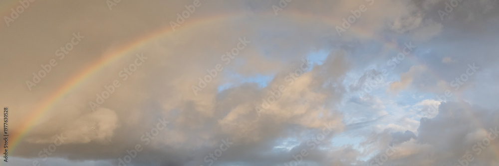 Obraz premium a rainbow in the sky with scattering clouds after rain