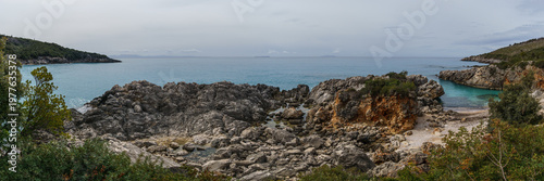 Panorama of aquarium bay with beach and rock formations on the Adriatic sea coast with turquoise colored water near Himare, Albania