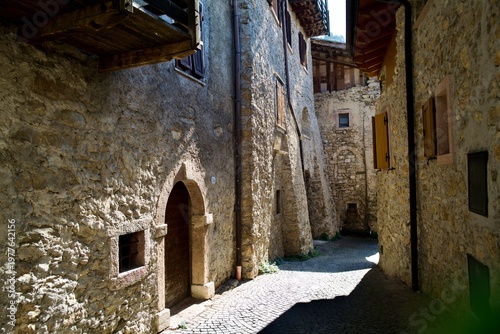 Sunlit medieval stone alley with arched doors in an Italian hill village