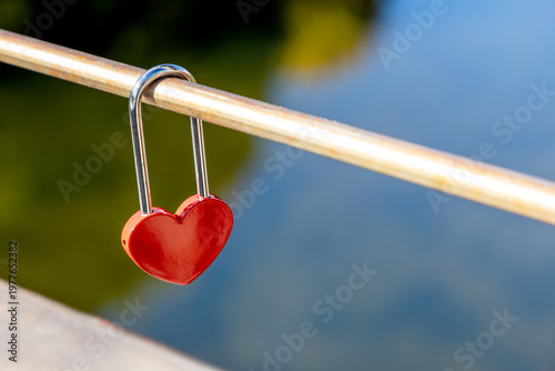 Red heart shaped padlock on metal railing, love symbol