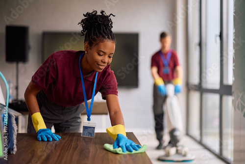 Schilderij op canvas Black female cleaning technician maintaining cleanliness of office building