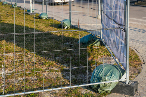 Photography Metal temporary fence secured with sandbags along sidewalk construction site saf