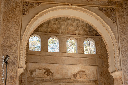 Ornate stucco archway and windows revealing ancient moorish architecture inside the historic nasrid palace, alhambra, granada