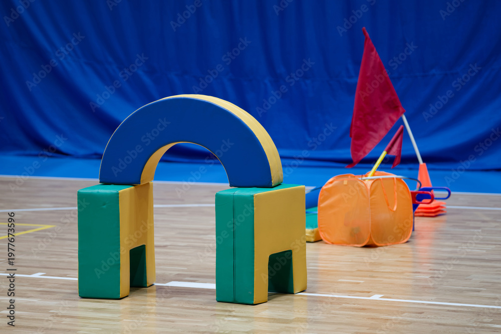 Obraz premium Soft foam sports equipment for kids obstacle course on an indoor gym floor. Training inventory for school physical education lessons, relay competitions and family sport activities. Photo