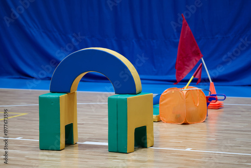 Soft foam sports equipment for kids obstacle course on an indoor gym floor. Training inventory for school physical education lessons, relay competitions and family sport activities. Photo