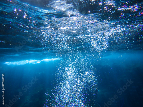 Ocean blue underwater with sunrays, Underwater Sea Deep Water Abstract Sunshine, sea wave , clean waters in summer time, Natural underwater seascape, sand on ocean floor and water surface sunlight.