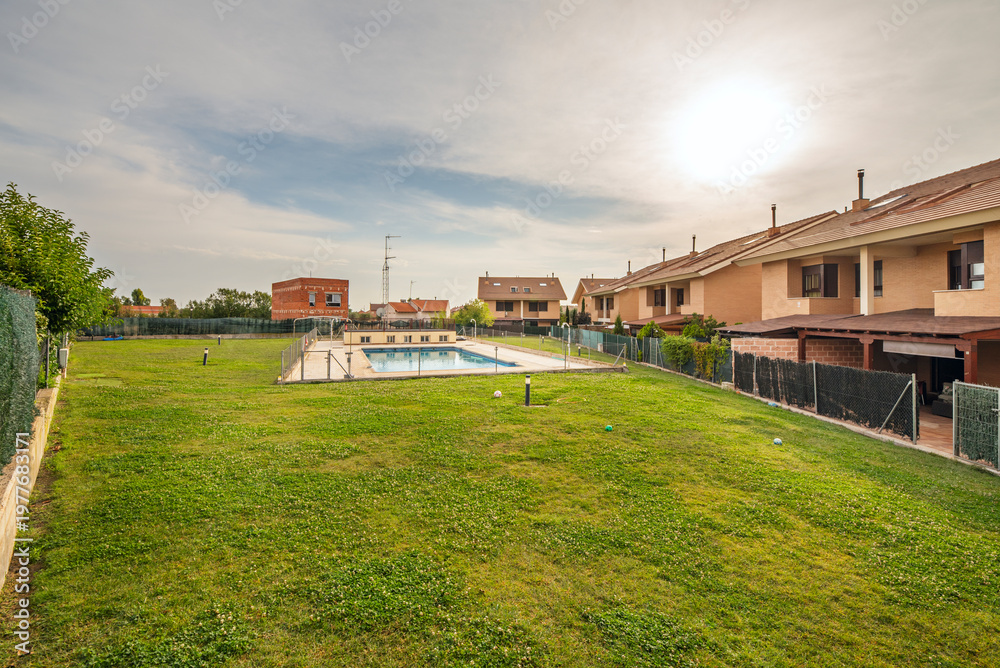 Obraz premium Irregularly shaped pool with a central island and artificial palm trees, surrounded by concrete planters with bougainvillea and modern-style lampposts