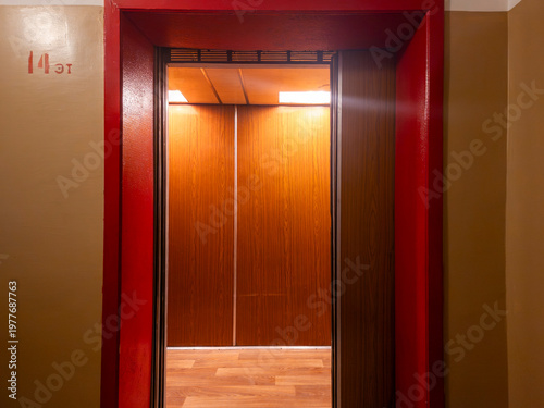Fotografi Elevator doors opening in a building hallway, revealing a warm lit interior with