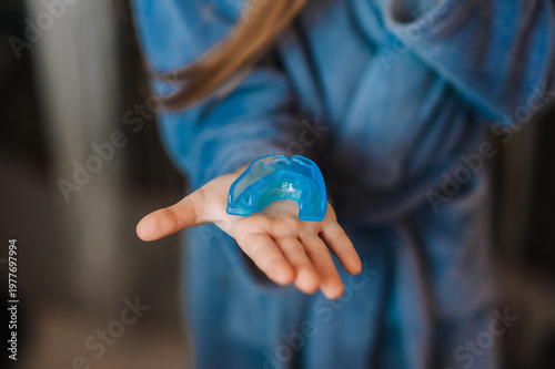 Girl, child holds blue silicone mouth guard in hand, braces for teeth alignment. Dentistry concept.