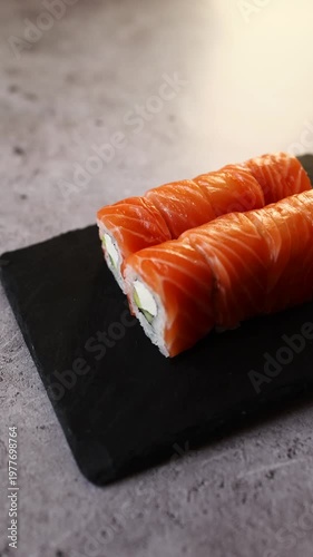 Fresh salmon sushi rolls on a sleek black stone surface showcasing vibrant colors and fresh ingredients