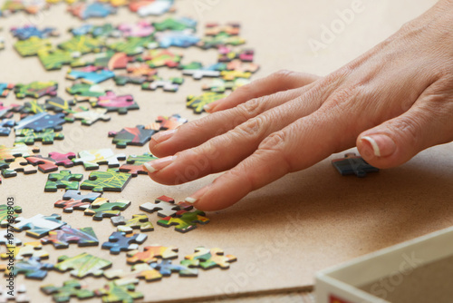 A woman is assembling puzzles at home in natural light. Only hands are visible.