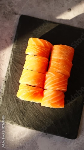Fresh salmon sushi served on a black slate plate illuminated by soft natural light creating an inviting culinary scene