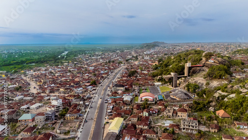 Aerial view of rooftops and a sprawling city blending into the horizon, with a prominent rock formation rising above the landscape, Ibadan, Nigeria.