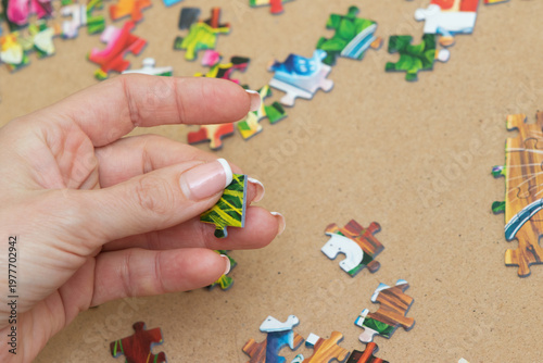 A woman is assembling puzzles at home in natural light. Only hands are visible.