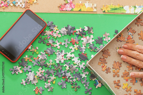 A woman is assembling puzzles at home in natural light. Only hands are visible.