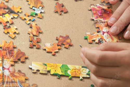 A teenage girl is putting together a puzzle. Only her hands are visible.