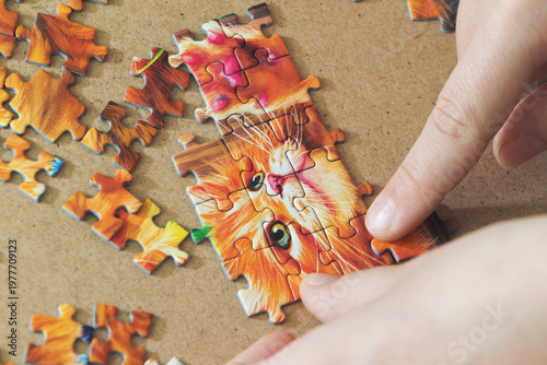 A teenage girl is putting together a puzzle. Only her hands are visible.