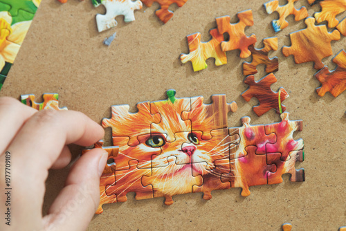 A teenage girl is putting together a puzzle. Only her hands are visible.