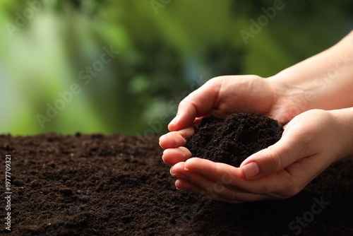 Woman with fresh soil on blurred background, closeup