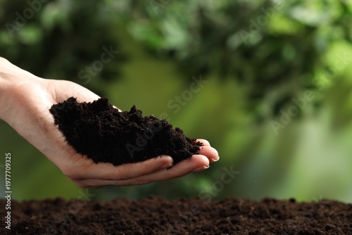 Woman with fresh soil on blurred background, closeup