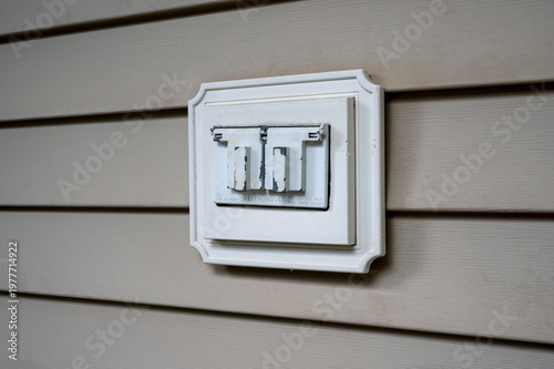Outdoor Electrical Outlet with Weatherproof Cover on House Exterior. residential electricity safety