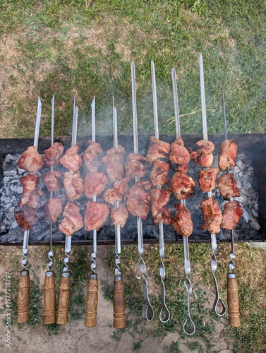 Grilled meat skewers cooking over charcoal on outdoor barbecue grill