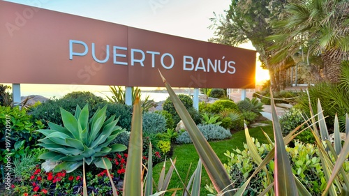 Puerto Banús sign with coastal garden landscaping and seaside promenade in Marbella, Andalusia, Spain