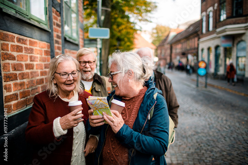 Senior friends reading map on historic cobblestone street