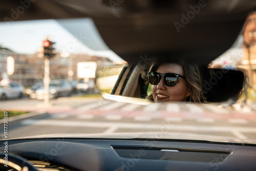 Foto Woman driving car smiling in rear-view mirror