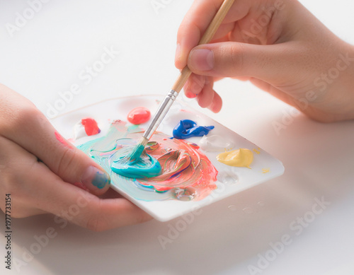 Hands delicately mixing acrylic paint with a brush.