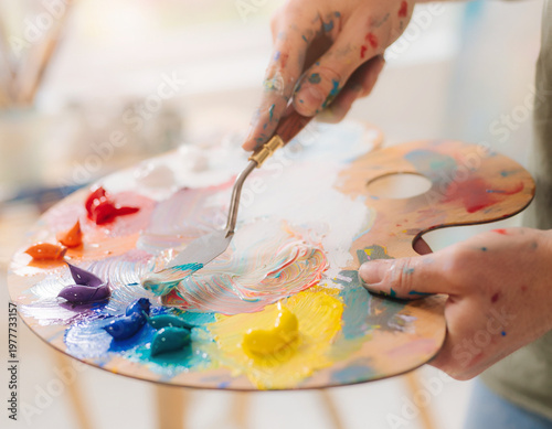 Hands delicately mixing acrylic paint with a brush.