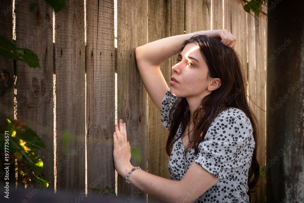 Obraz premium Young brunette woman by rustic wooden fence