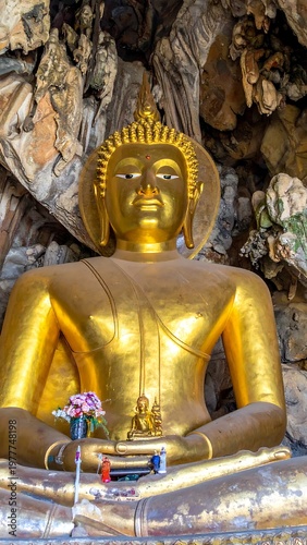 Golden Buddha statue seated in a cave with serene expression