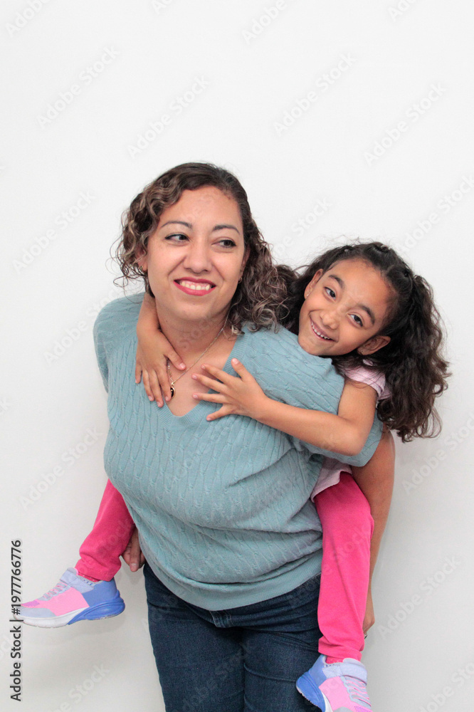 Fototapeta premium Latina single mom and her 5-year-old brunette daughter show their love with kisses and hugs to celebrate Mother's Day