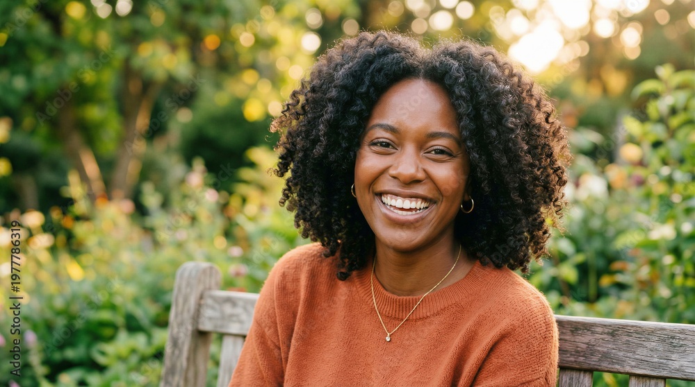 Fototapeta premium Happy African American Woman with Curly Hair Smiling in a Sunny Outdoor Garden