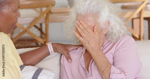 Vertical video: Friend soothing senior after cry, guiding hands to lap with animated health icon