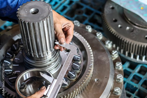 Slika na platnu Technician measuring heavy duty metal spline shaft gear using vernier caliper to