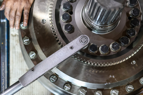 Bild auf Leinwand Top view Professional technician tightening heavy machinery gear bolts using manual torque wrench in industrial workshop