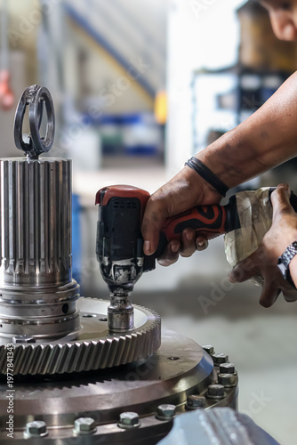Fotografi Technician using electric cordless impact wrench to tighten bolts on heavy metal
